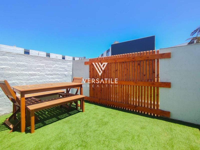 A private rear courtyard featuring artificial turf, a decorative timber privacy screen, and masonry boundary walls.