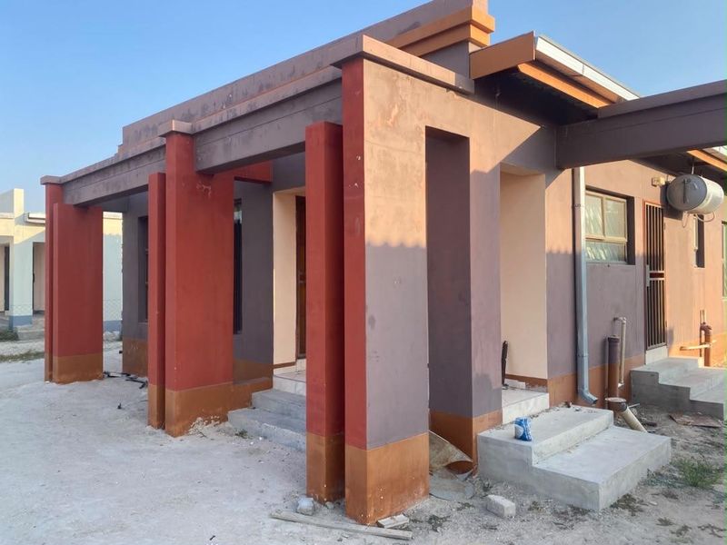 Front elevation of a house featuring a covered porch with prominent masonry columns, external geyser, and unfinished exterior finishes.