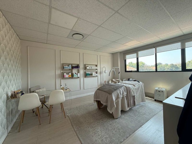 A well-maintained office space featuring decorative wall molding, a suspended ceiling with recessed lighting, and large windows providing ample natural light.