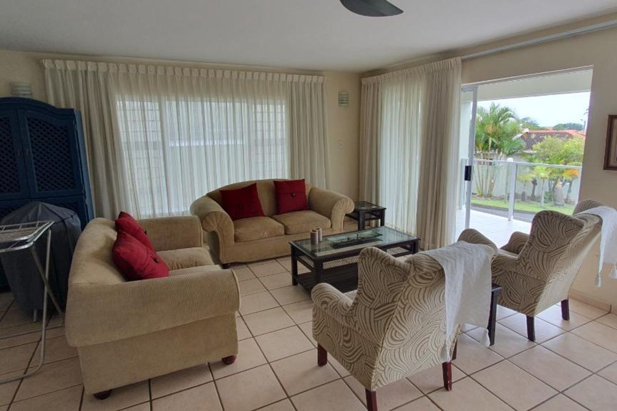 Spacious living room featuring ceramic tile flooring, a ceiling fan, and large sliding glass doors providing access to an outdoor patio area.
