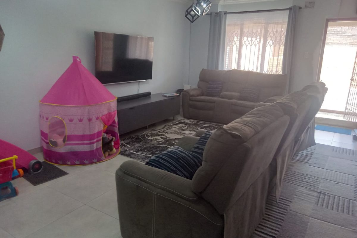 A comfortable living room featuring tiled flooring, modern lighting, and a security gate leading to the exterior.