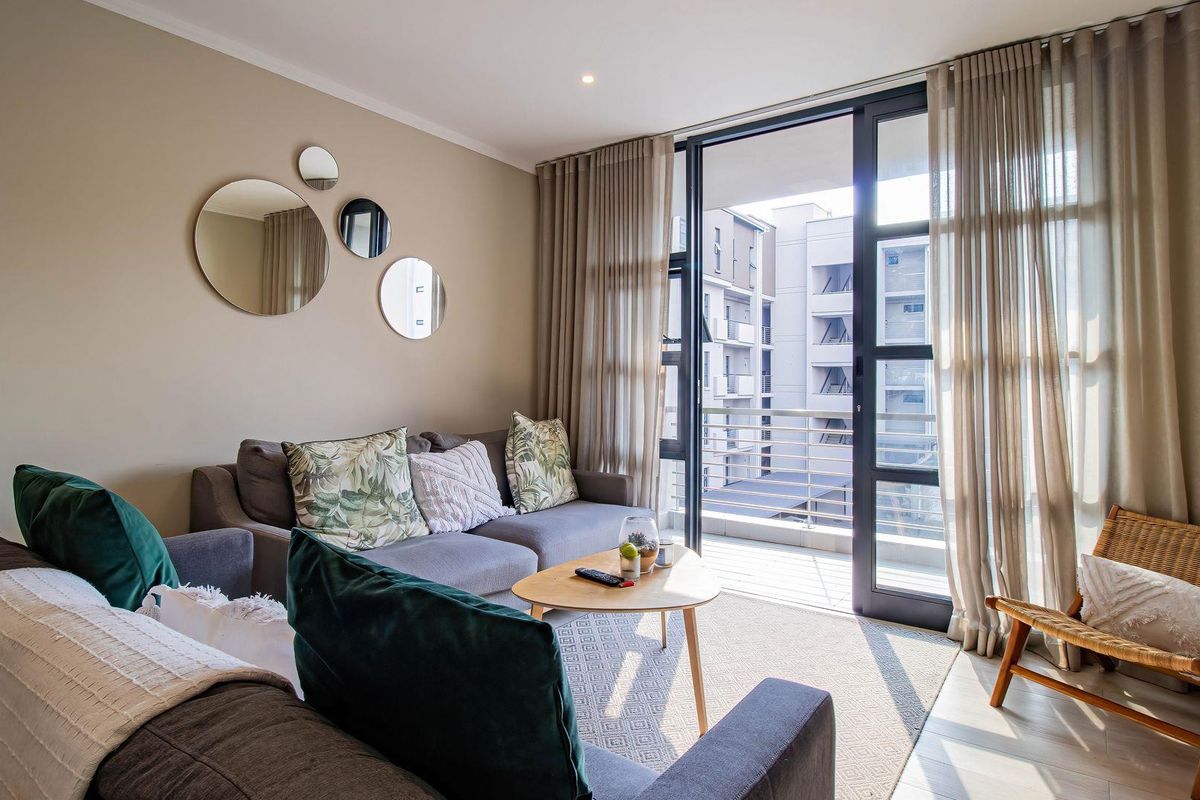 A bright living room featuring tiled flooring, recessed lighting, and a large sliding glass door providing access to a balcony.
