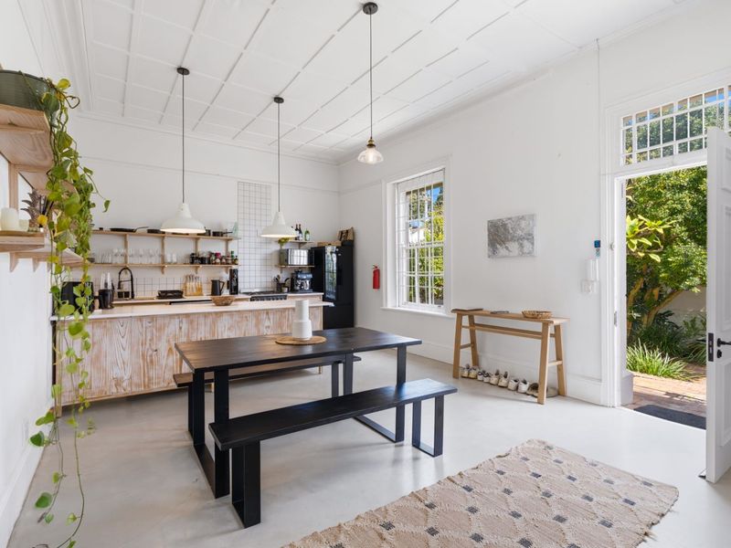 Spacious open-plan kitchen and dining area featuring a unique coffered ceiling, timber cabinetry, and direct access to a lush garden through a classic panelled door.