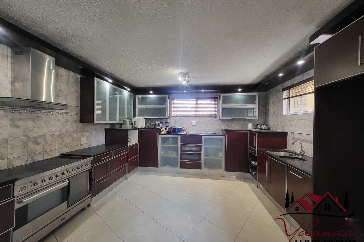 Spacious kitchen featuring dark wood cabinetry, stainless steel appliances, tiled flooring, and a functional layout with ample counter space.