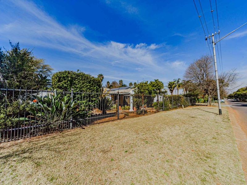 Street view of the property showing the front boundary with metal fencing, landscaped garden, and solar panels installed on the roof.
