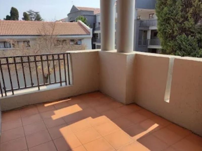 A covered balcony featuring tiled flooring, structural pillars, and a metal railing, offering an outdoor space for relaxation.