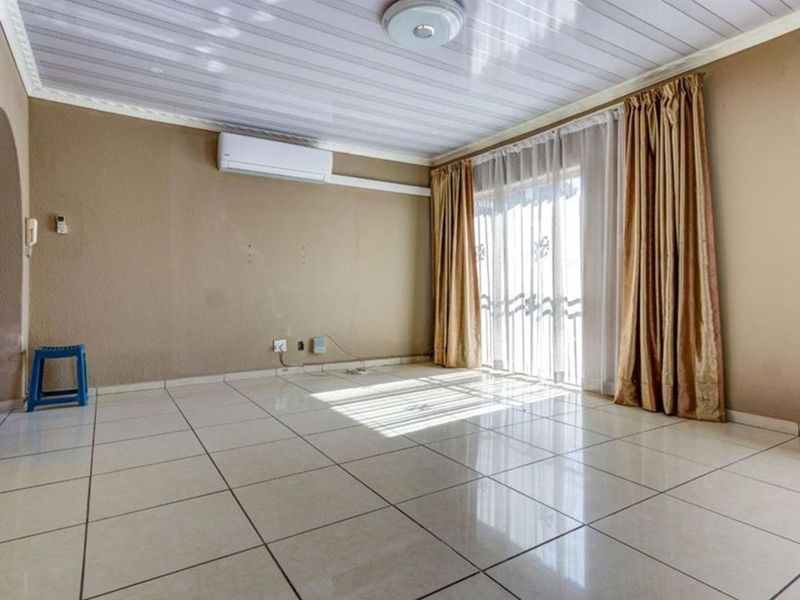 An empty living room featuring tiled flooring, a split-system air conditioner, and a sliding glass door providing access to the exterior.