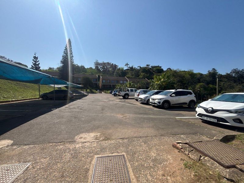 Exterior view of the apartment complex parking area featuring asphalt surfacing and shade cloth carports.