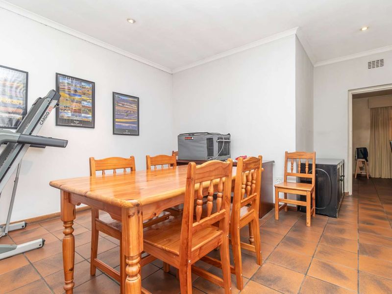 A functional dining area featuring durable tiled flooring and recessed downlighting, providing a neutral space ready for modern updates.