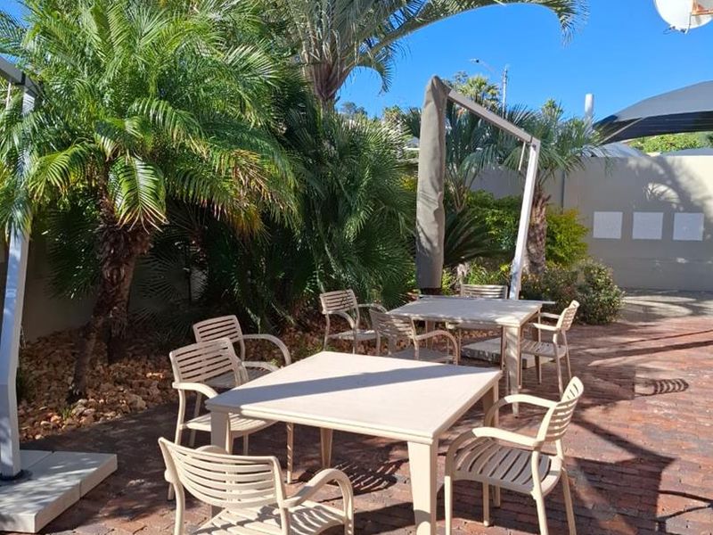 Outdoor patio area featuring brick paving and established palm trees, providing a pleasant space for office staff or client relaxation.