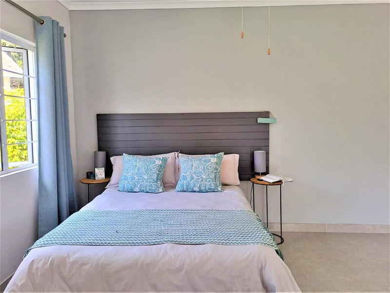 A well-maintained bedroom featuring neutral wall tones, tiled flooring, and a large window allowing for natural light.