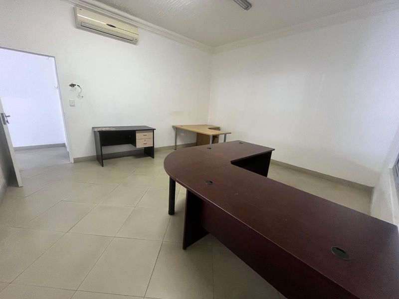 A functional office space featuring tiled flooring, coving, and a wall-mounted split-system air conditioner.