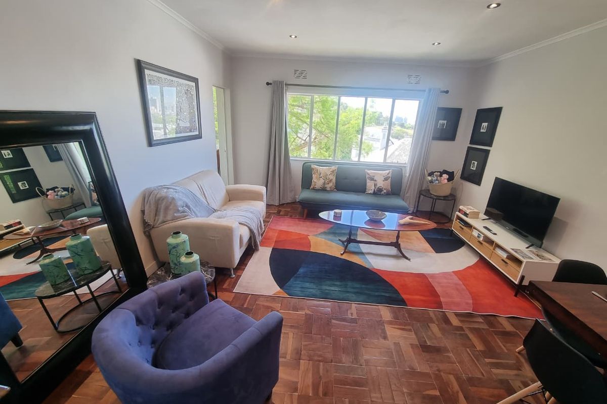 A bright and inviting living room featuring classic parquet flooring and recessed downlights, offering a comfortable space with natural light.