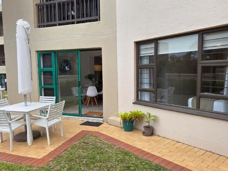 A ground floor patio area featuring paved flooring, sliding door access to the interior, and aluminium-framed windows with security bars.