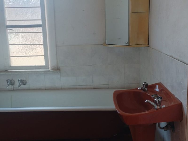 A dated bathroom featuring a classic bathtub and pedestal basin, requiring renovation to modernize the space and improve overall condition.
