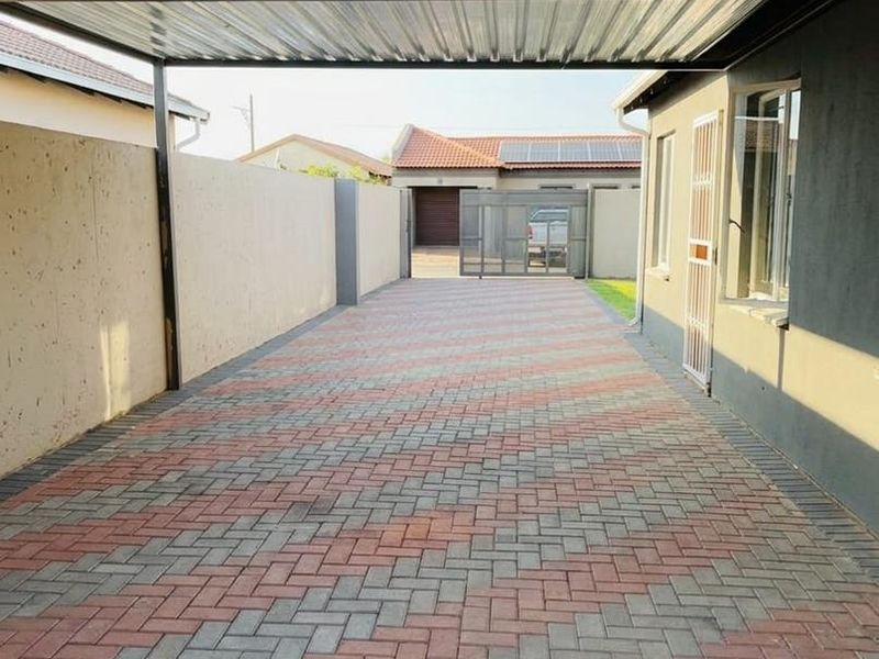 A covered carport area featuring paved flooring and secure boundary walls, providing convenient off-street parking.