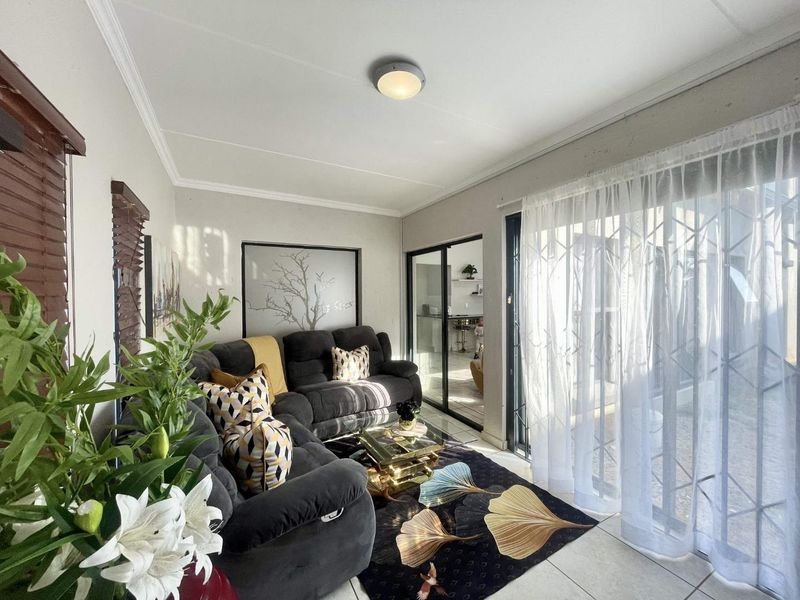 A bright living room featuring tiled flooring, a ceiling light fixture, and large sliding glass doors that provide access to the outdoor area.