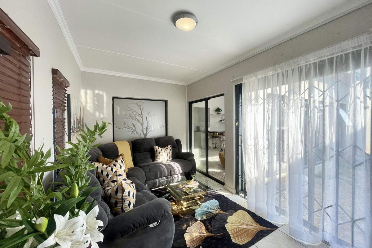 A bright living room featuring tiled flooring, a ceiling light fixture, and large sliding glass doors that provide access to the outdoor area.