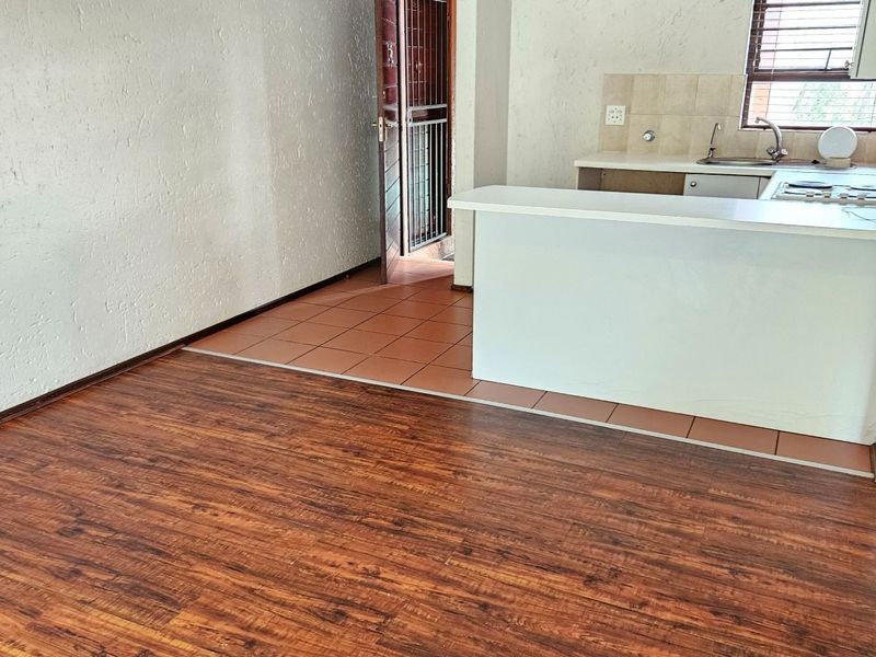 Open plan living area featuring a kitchen with a breakfast bar, tiled and laminate flooring, and direct access to a secure entrance.