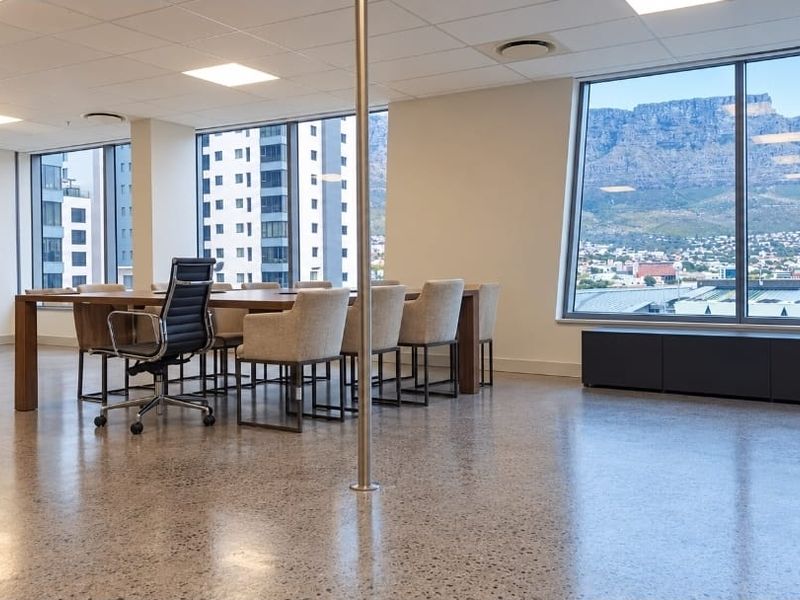 Modern office space featuring polished concrete floors, suspended ceilings, and expansive windows offering panoramic mountain and city views.