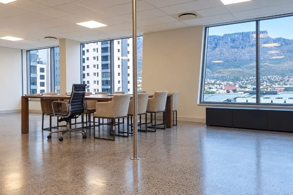 Modern office space featuring polished concrete floors, suspended ceilings, and expansive windows offering panoramic mountain and city views.