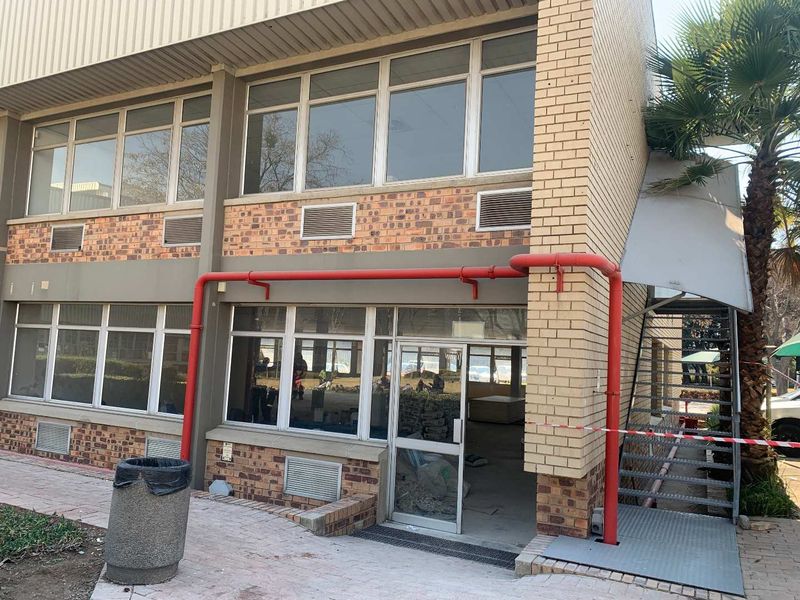 Front elevation of an industrial building featuring brick facade, large windows, external fire safety piping, and an external metal staircase.