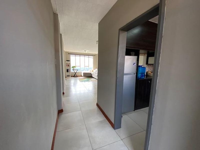 A view from the hallway looking into the open plan living area and kitchen, featuring neutral tiled flooring and clean wall finishes.