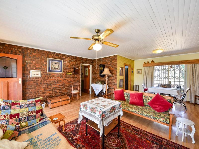A living room featuring exposed brick walls, timber ceiling, and laminate flooring, offering a rustic aesthetic with potential for modern updates.