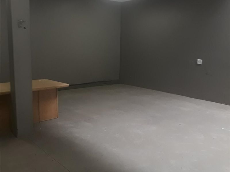 An empty industrial office space featuring concrete flooring, a structural column, and a skylight providing natural light.