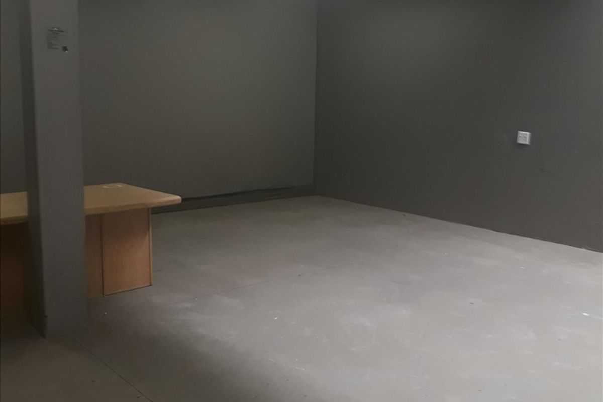An empty industrial office space featuring concrete flooring, a structural column, and a skylight providing natural light.