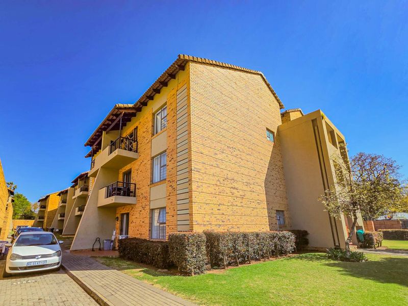 Exterior view of a multi-story apartment complex featuring face brick construction, private balconies, and well-maintained surrounding garden areas.