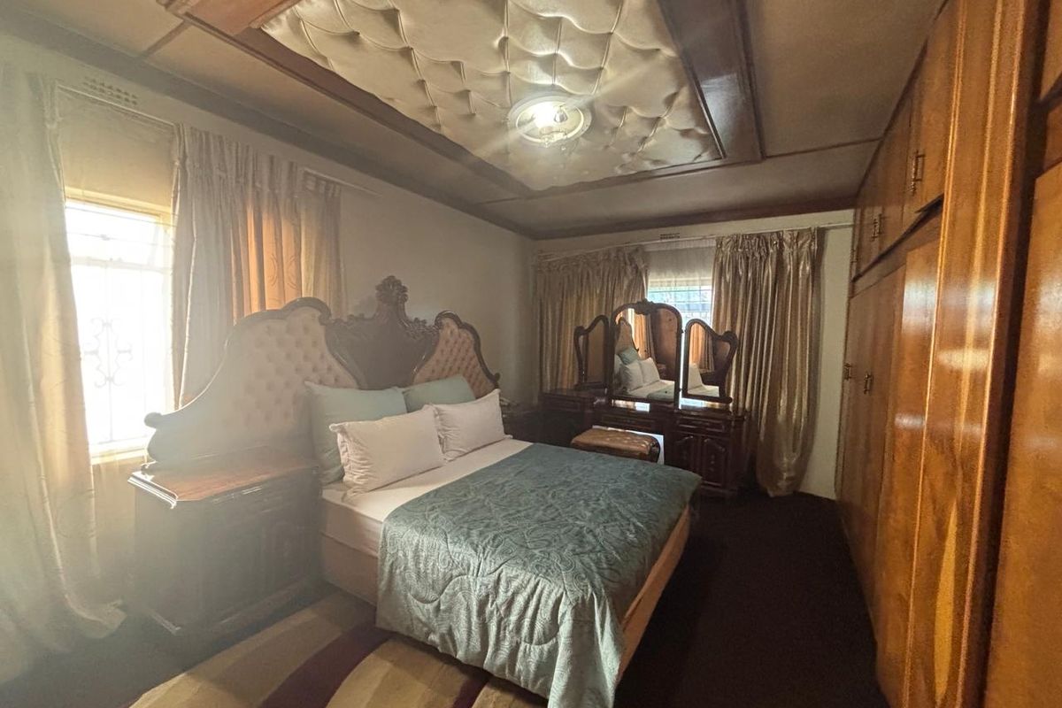 A spacious bedroom featuring built-in wooden cabinetry, a unique tufted ceiling detail, and large windows allowing for natural light.