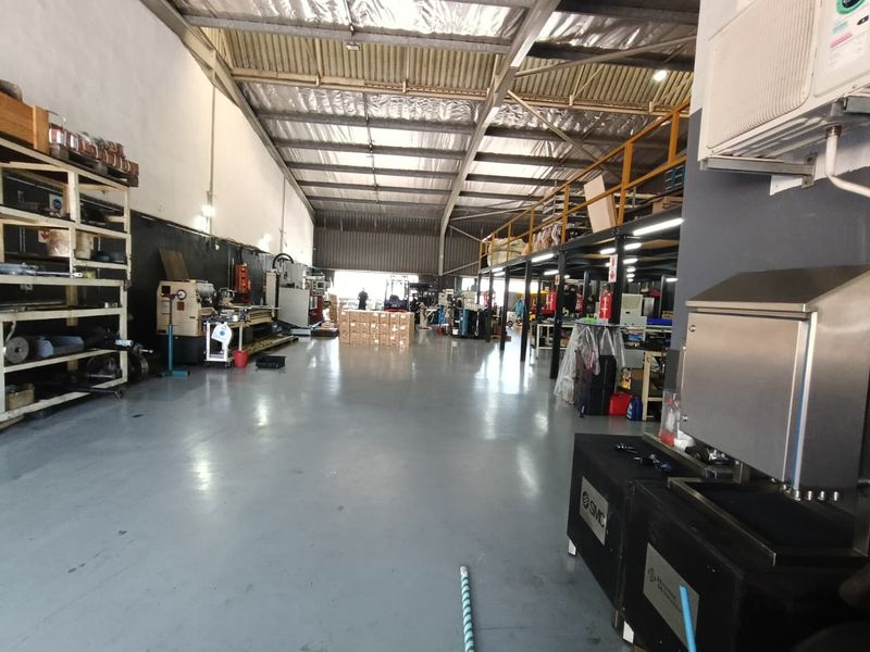 Spacious industrial warehouse featuring high ceilings with exposed steel trusses, a mezzanine level, and durable epoxy-coated flooring suitable for manufacturing or storage operations.