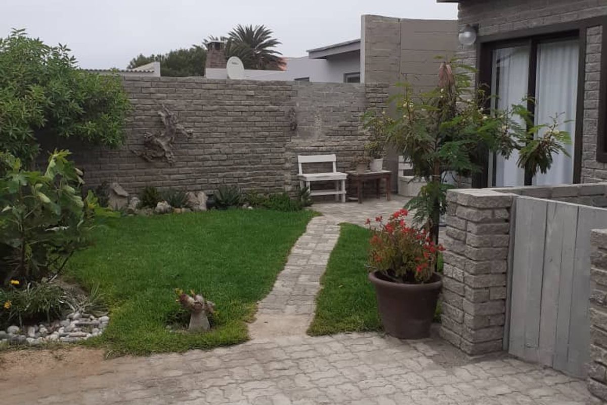 A private rear garden featuring a paved patio area, a small lawn, and a brick boundary wall, providing a quiet outdoor space.