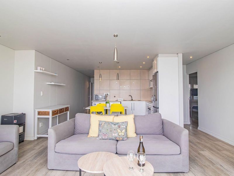 Modern open-plan living area featuring a seamless transition between the lounge and a functional kitchen with built-in cabinetry and integrated appliances.