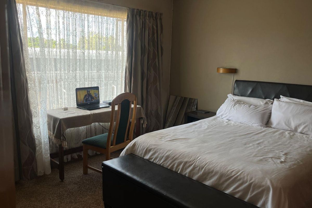 A bedroom featuring carpeted flooring and a large window with curtains, providing natural light to the space.