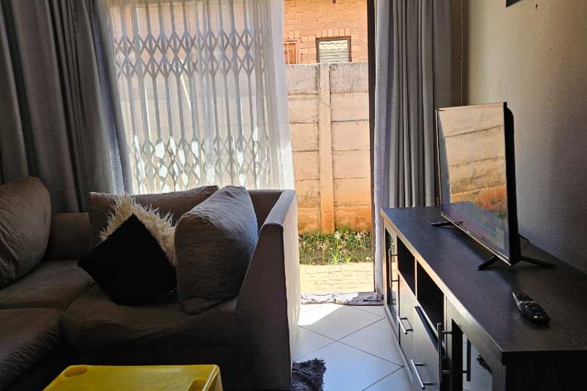 A living room featuring tiled flooring and a sliding door providing direct access to a private outdoor patio area.
