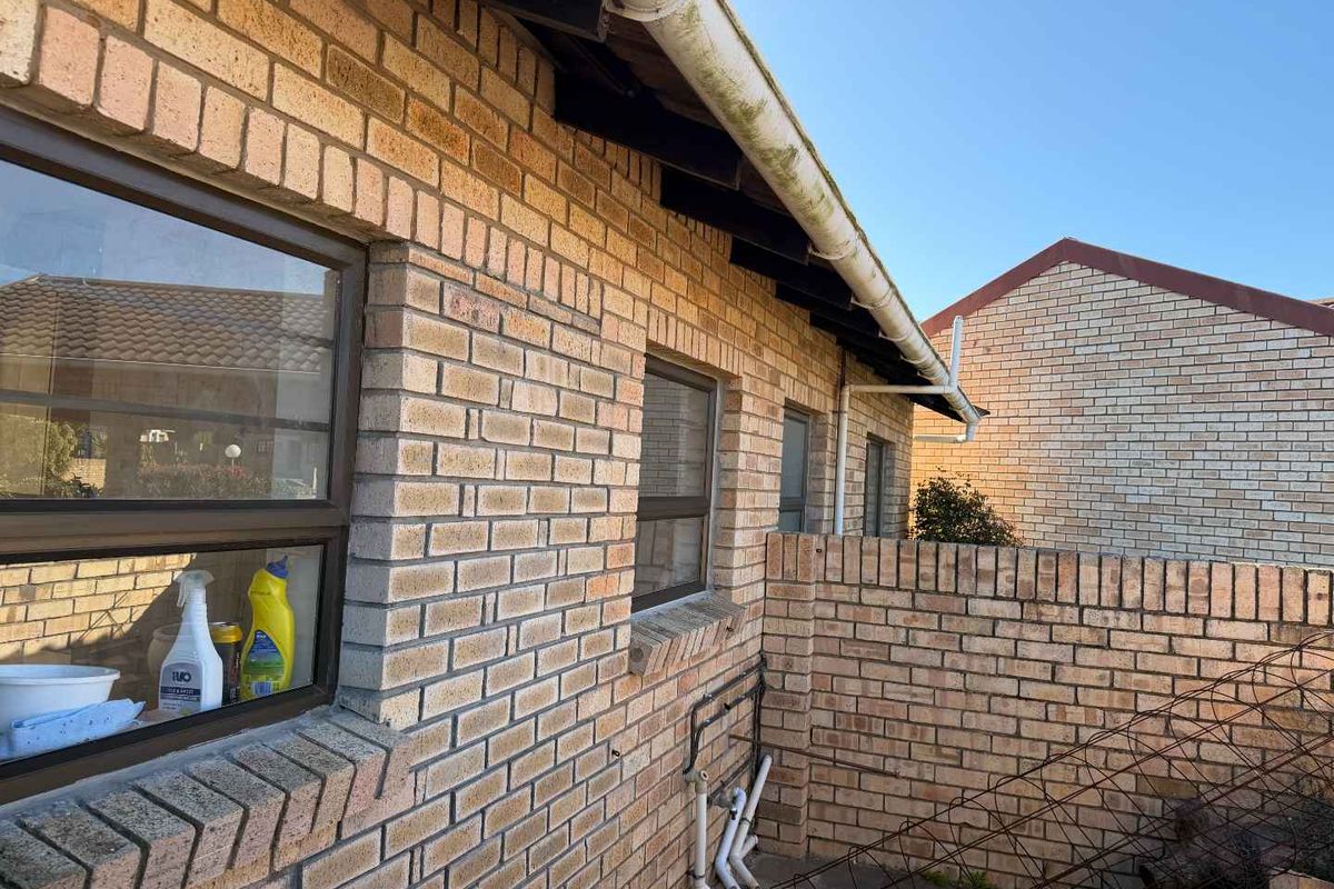 Rear exterior view of the townhouse featuring face brick construction, aluminium window frames, and existing guttering system.