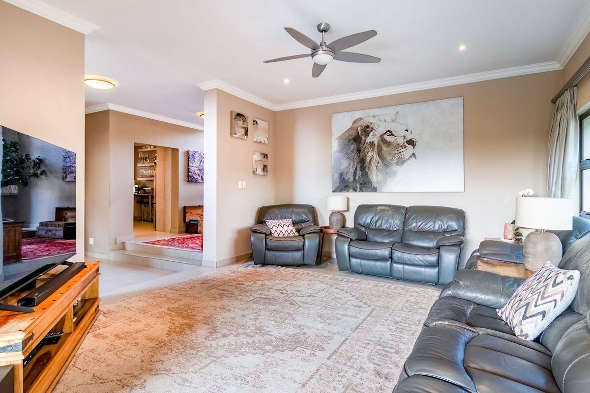 Spacious living room featuring a ceiling fan, neutral wall tones, and an open-plan layout leading to an adjacent area.