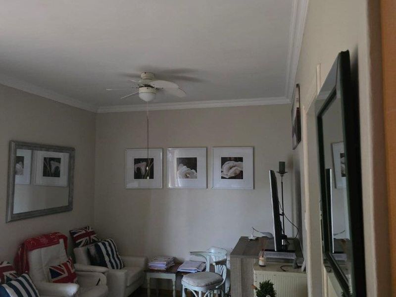 A cozy living room featuring tiled flooring, crown molding, and a ceiling fan, offering a comfortable and functional space.