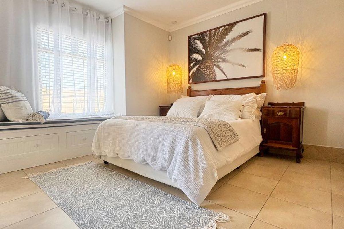 A well-maintained bedroom featuring tiled flooring, a built-in window seat, and a modern ceiling fan, creating a bright and comfortable living space.