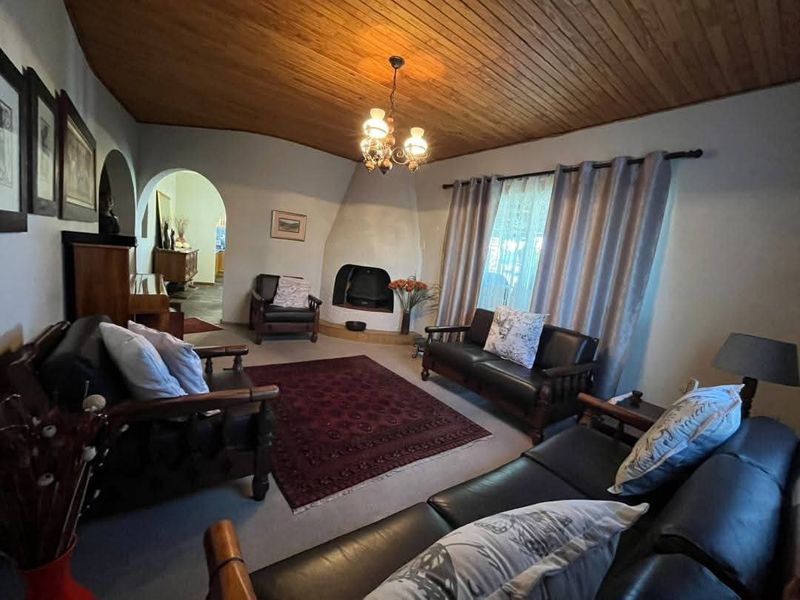 A cozy living room featuring a unique built-in fireplace, a distinctive timber-clad vaulted ceiling, and an arched entryway leading to adjacent living spaces.