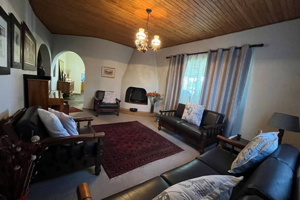 A cozy living room featuring a unique built-in fireplace, a distinctive timber-clad vaulted ceiling, and an arched entryway leading to adjacent living spaces.