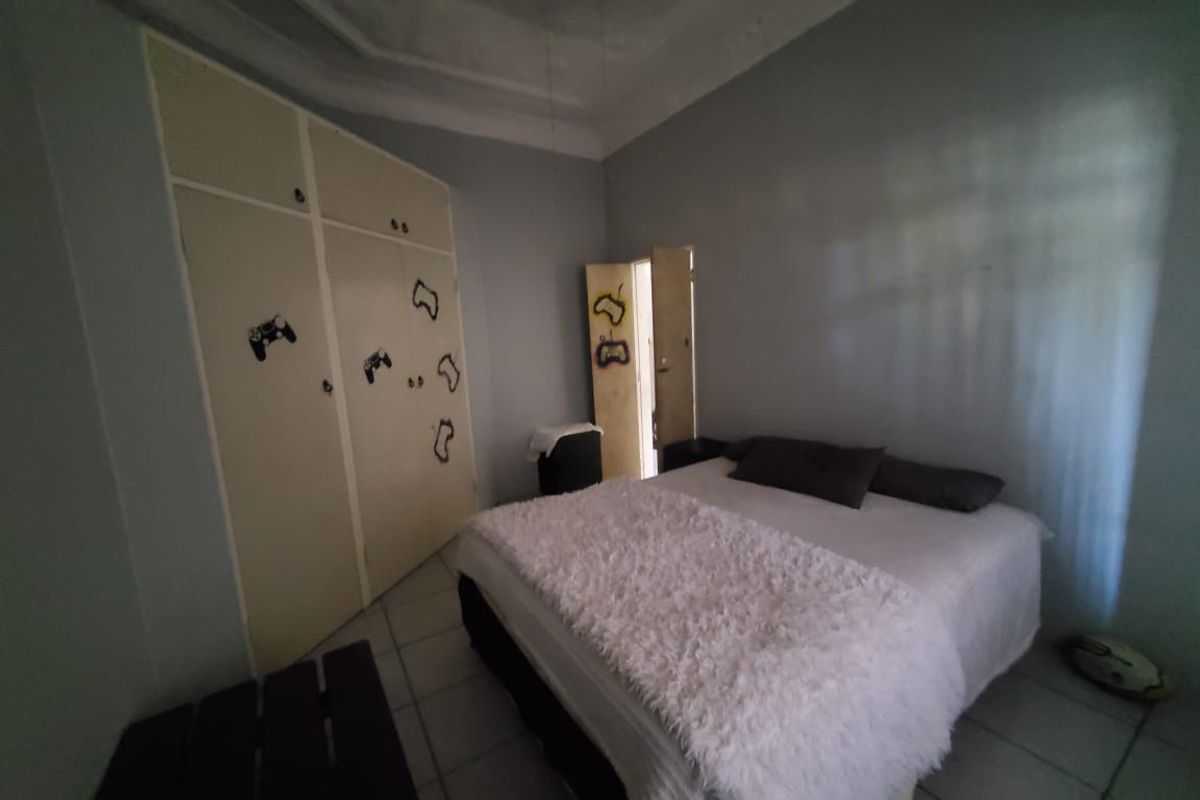 A bedroom featuring built-in cupboards with a tray ceiling design and tiled flooring.