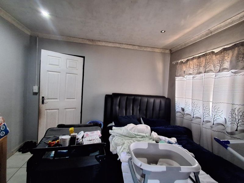 A bedroom featuring recessed downlights and decorative coving, currently showing signs of wear on the ceiling and walls.