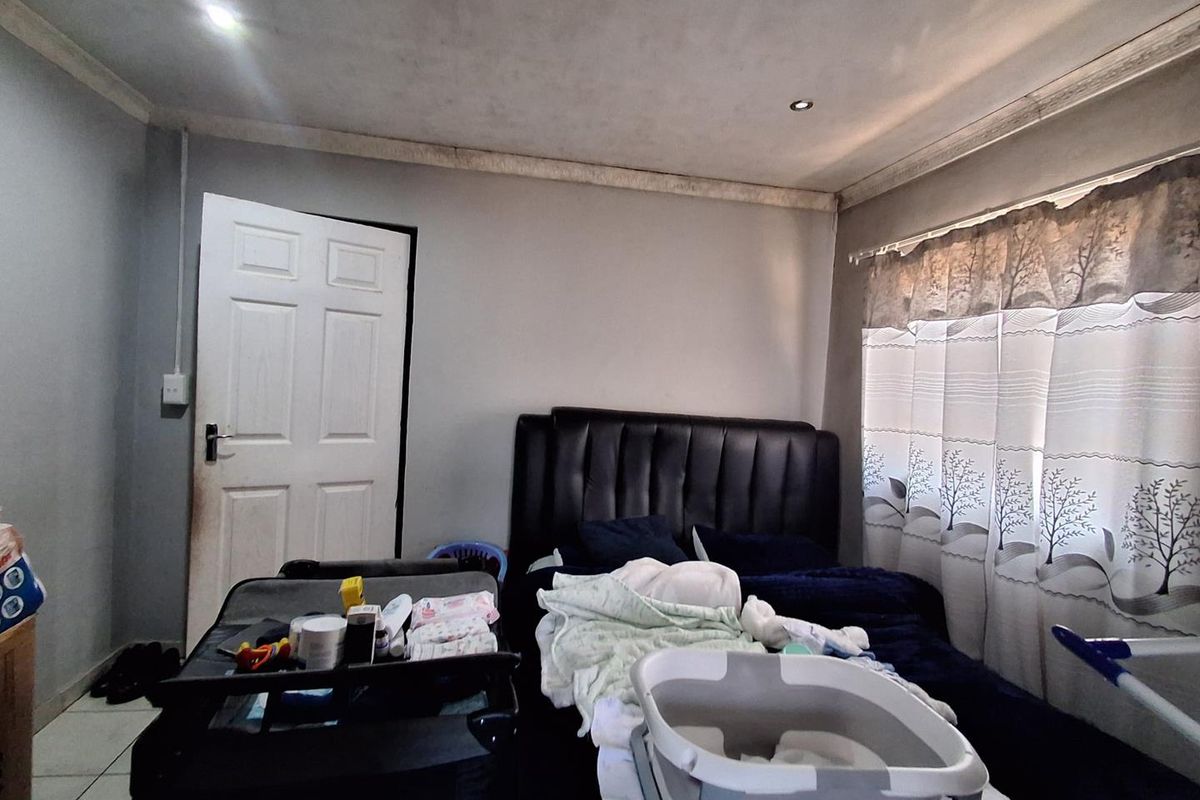 A bedroom featuring recessed downlights and decorative coving, currently showing signs of wear on the ceiling and walls.
