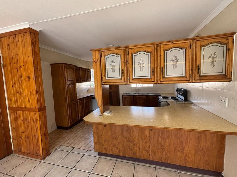 A functional kitchen featuring traditional wooden cabinetry, laminate countertops, tiled backsplash, and ceramic flooring, offering a classic layout ready for modern updates.