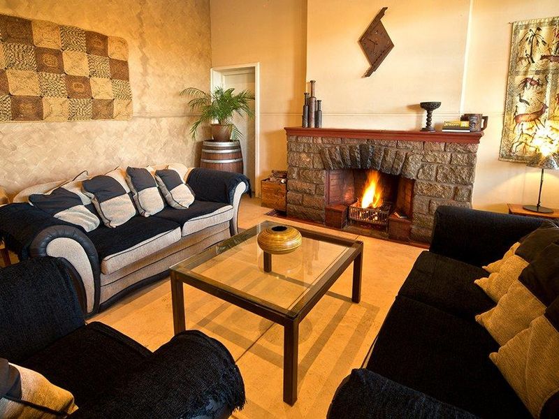 Cozy hotel lounge area featuring a prominent stone fireplace and textured wall finishes, creating a warm and inviting atmosphere.