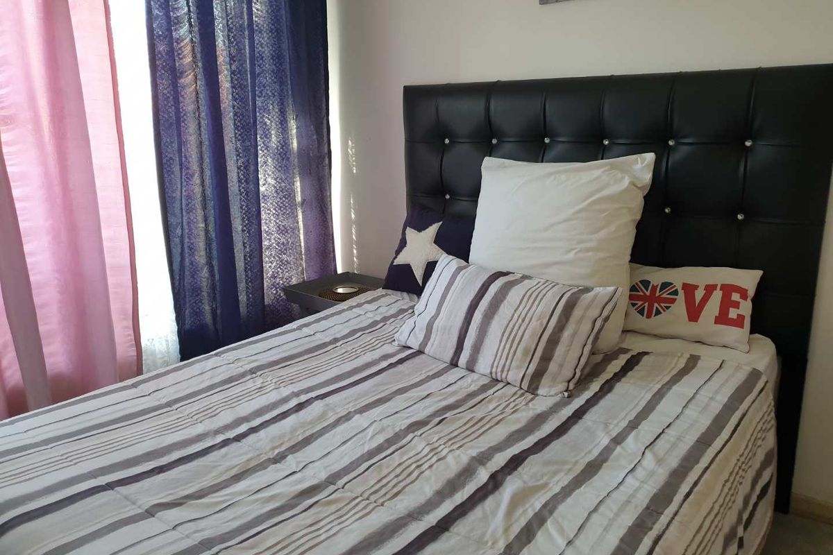 A bedroom featuring a tufted headboard and window treatments.