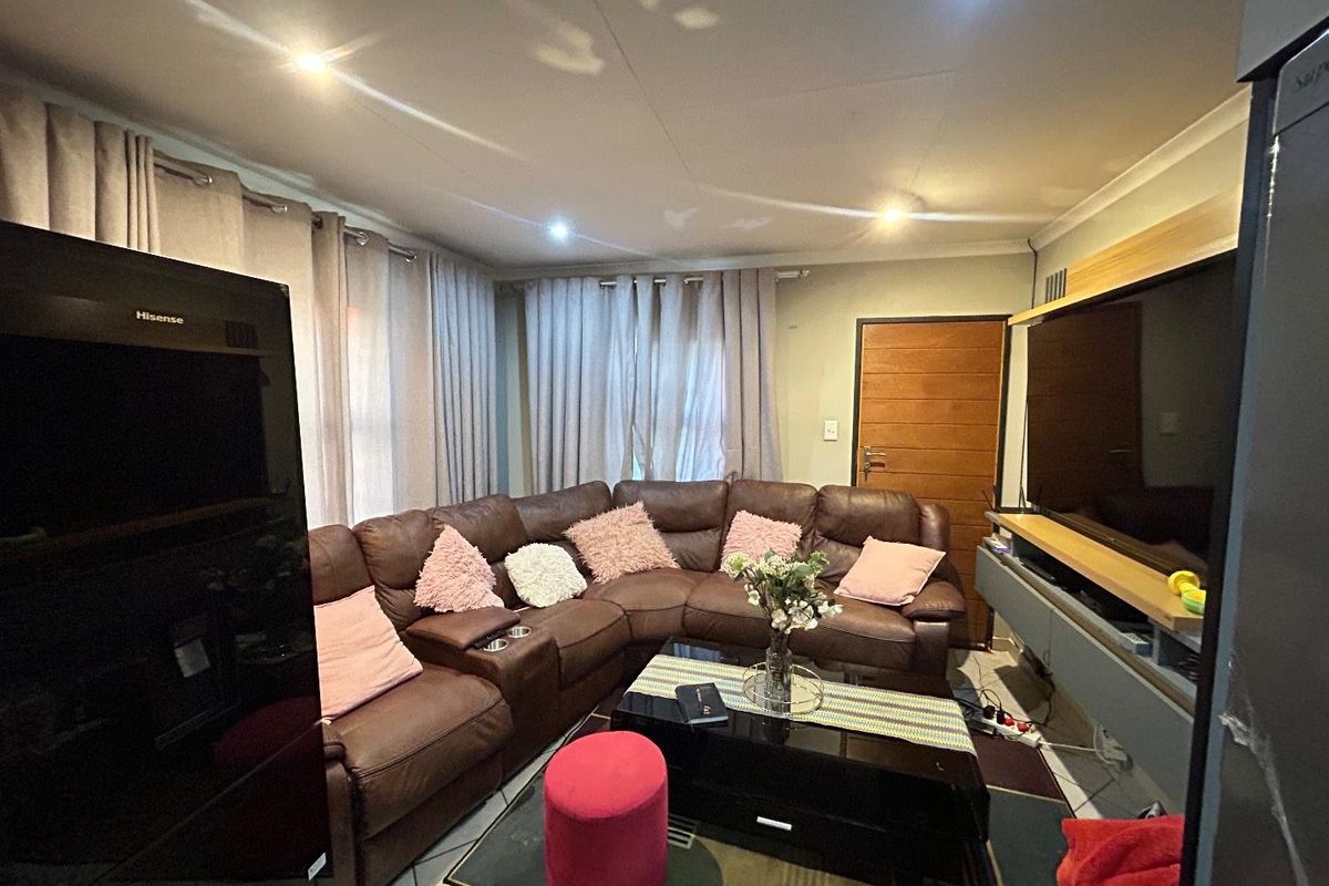 A cozy living room featuring tiled flooring, recessed ceiling lighting, and a built-in media console unit.